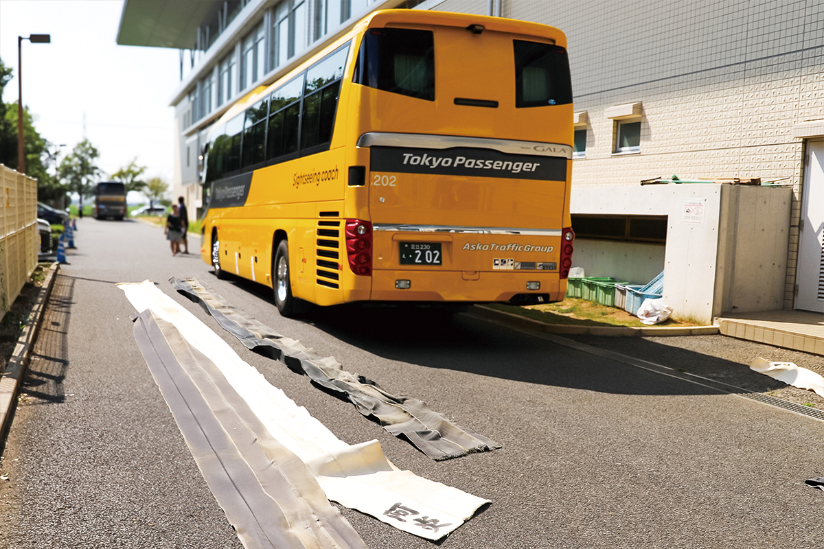 廻しの天日干しと並ぶ東京パッセンジャーのバス